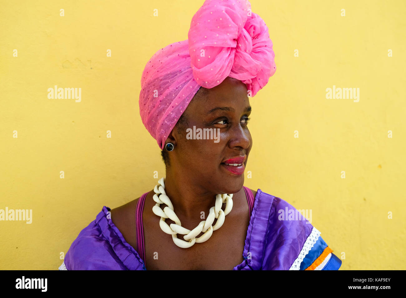 A Cuban woman wears brightly coloured clothes as she sits on the streets of Havana, Cuba. Stock Photo