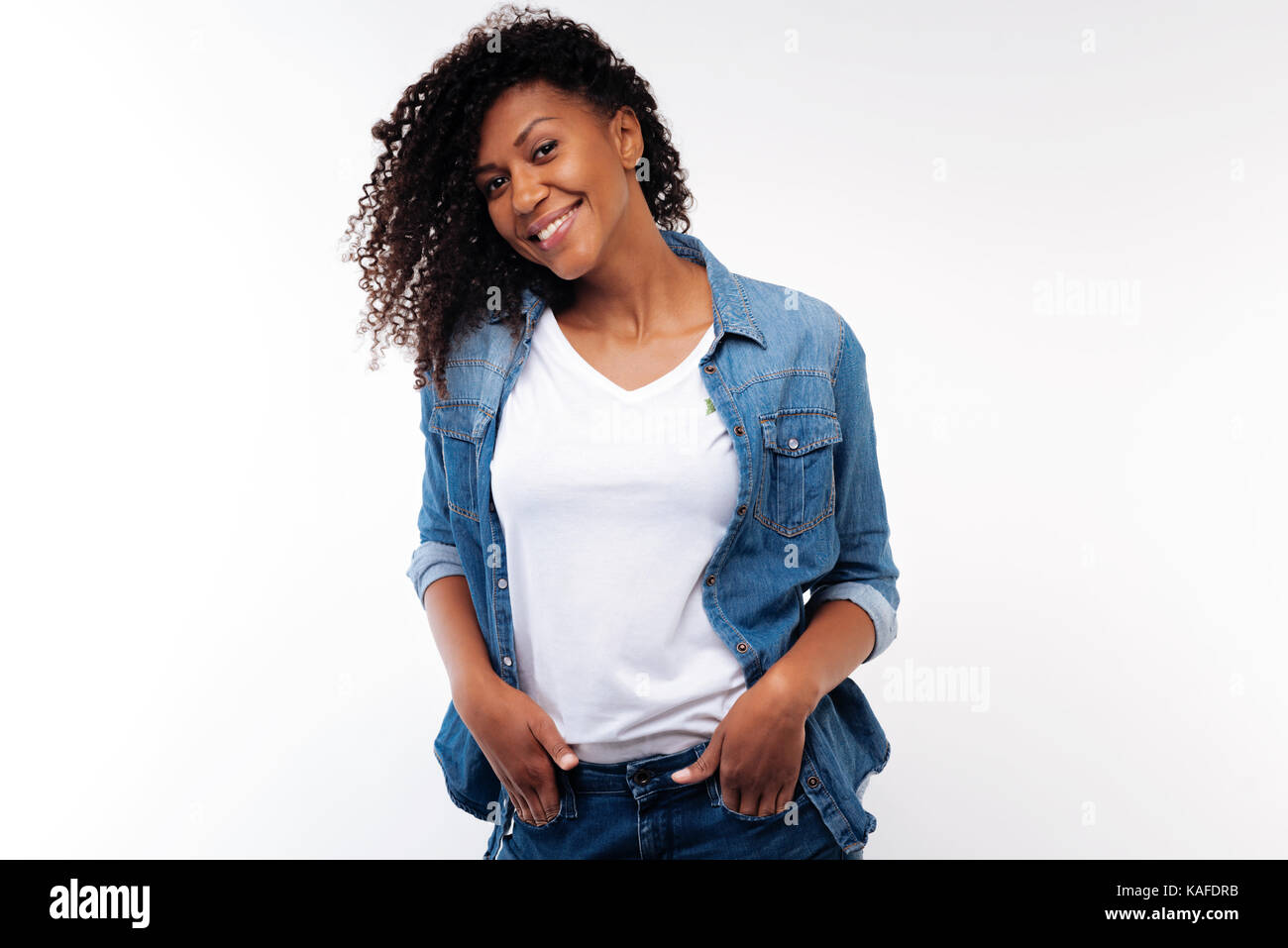 Charming curly woman holding hands in pockets of jeans Stock Photo
