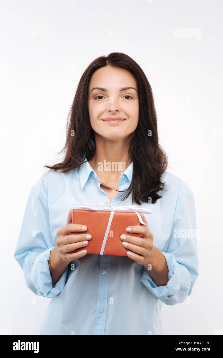 Smiling woman holding a gift box in both hands Stock Photo - Alamy