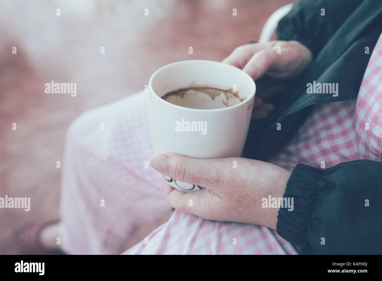 Hospital patient holding mug and drinking coffee. Female person with cup of hot beverage. Selective focus image toned with retro filter. Stock Photo