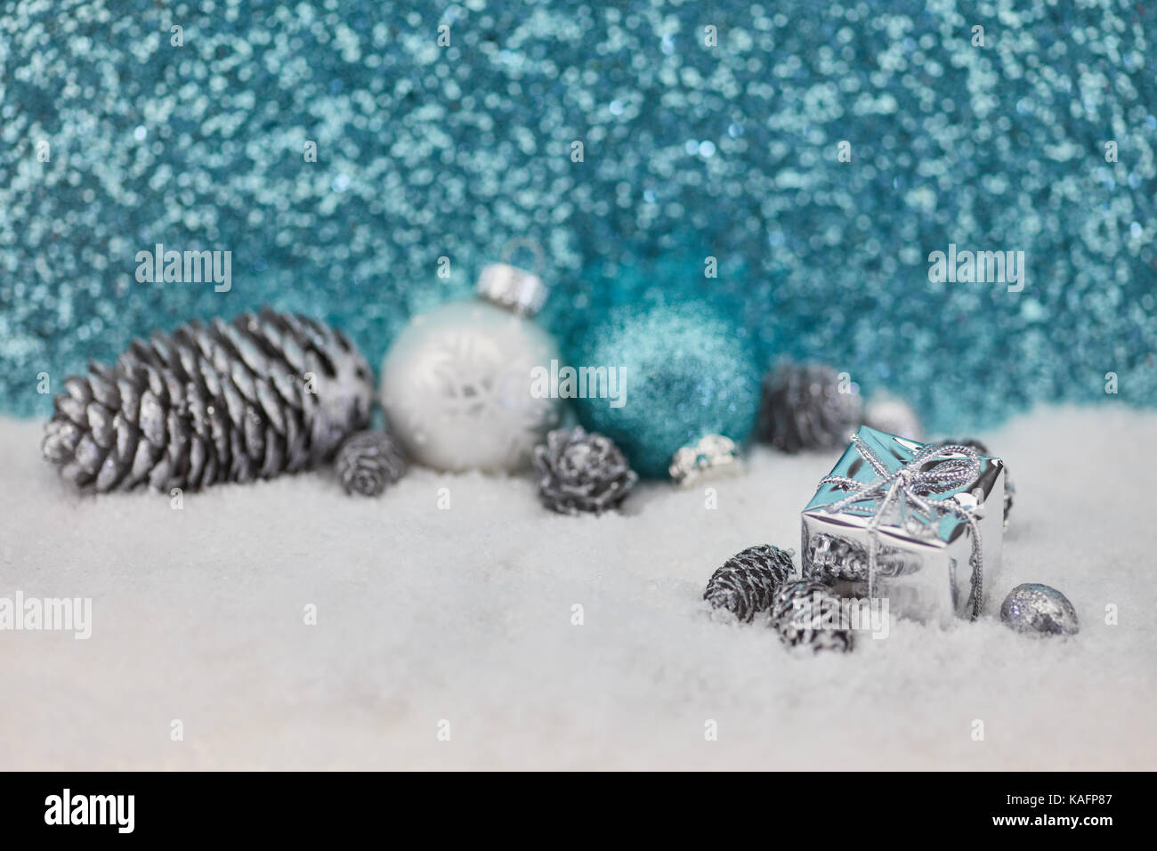 Blue glitter christmas background with gift and baubles on snow Stock