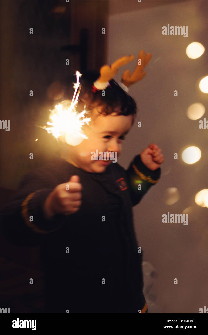 Little happy kid holding a sparkling stick and dancing with joy Stock Photo