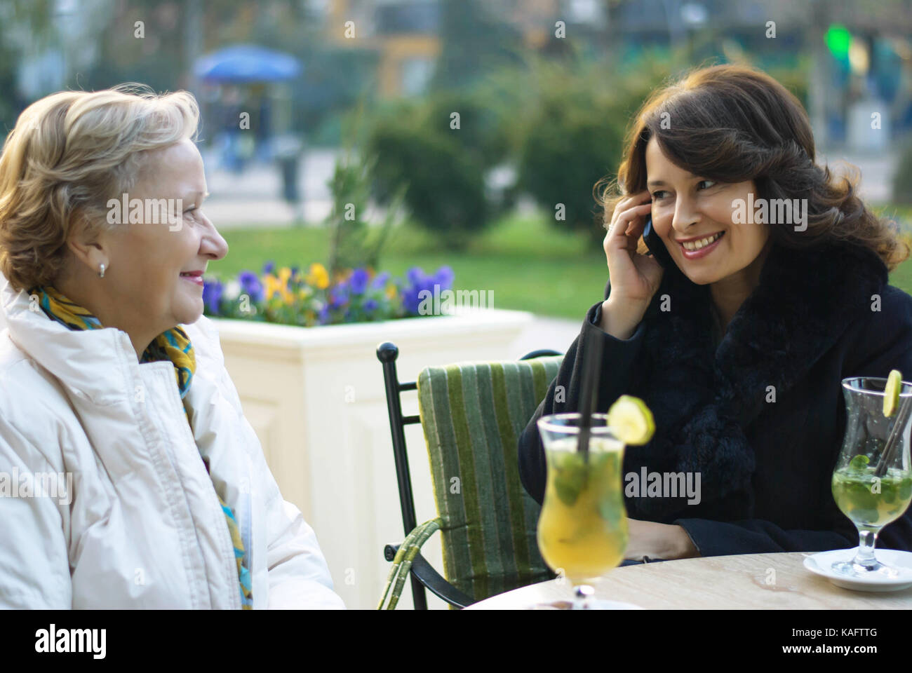 Two middle-aged women hang out in the cafe, after a sunny autumn day Stock Photo