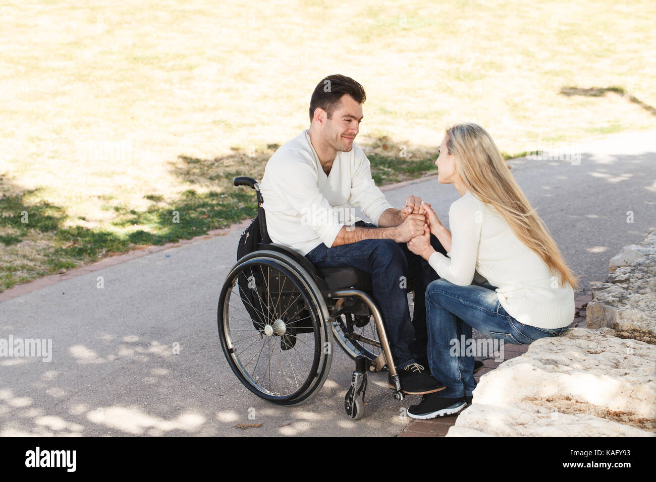Disabled man on a wheelchair talking with his girlfriend in the park ...