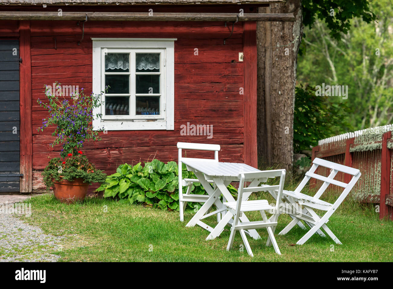 White wooden outdoor furniture outside a red traditional barn window
