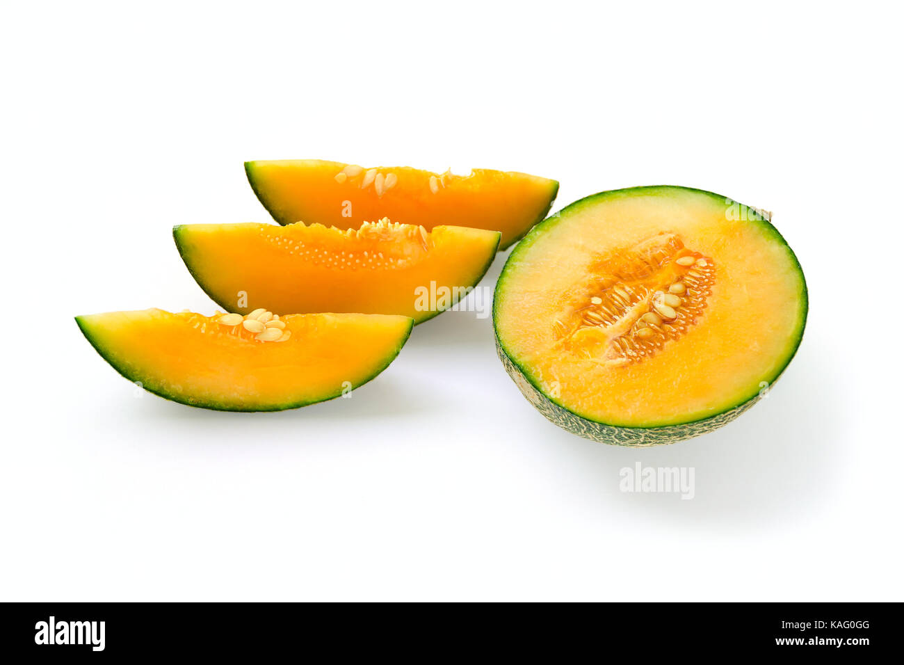 Cut halved ripe melon yellow inside, green outside. Near the cut slices with seeds. Isolate on white background. Stock Photo