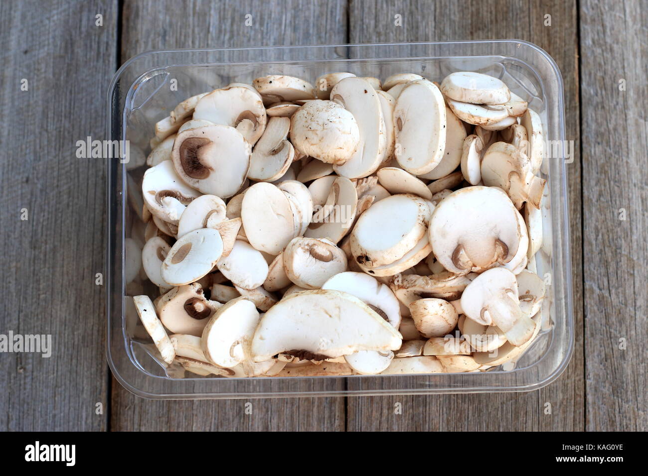 Close up of Sliced Agaricus bisporus or known as White Button Mushrooms against wooden background Stock Photo