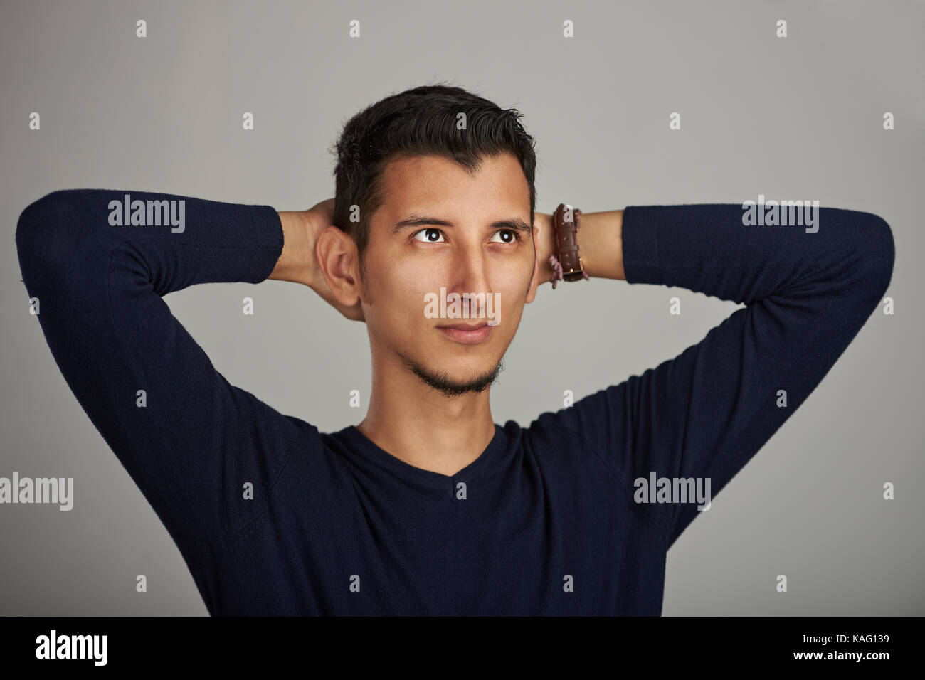 Young man with hands to head looking up Stock Photo