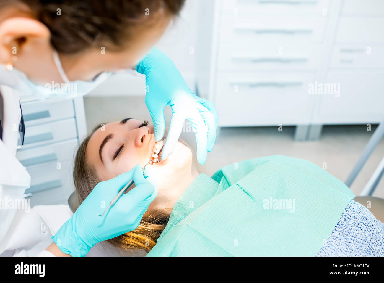 female-dentist-checking-up-patient-teeth-with-braces-at-dental-clinic-KAG1EX.jpg