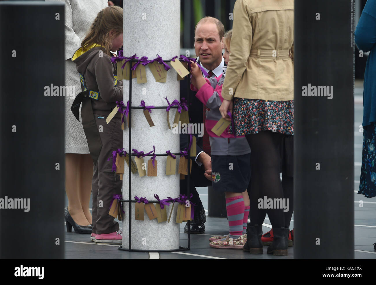 The Duke of Cambridge watches children tie name tags to a pillar during