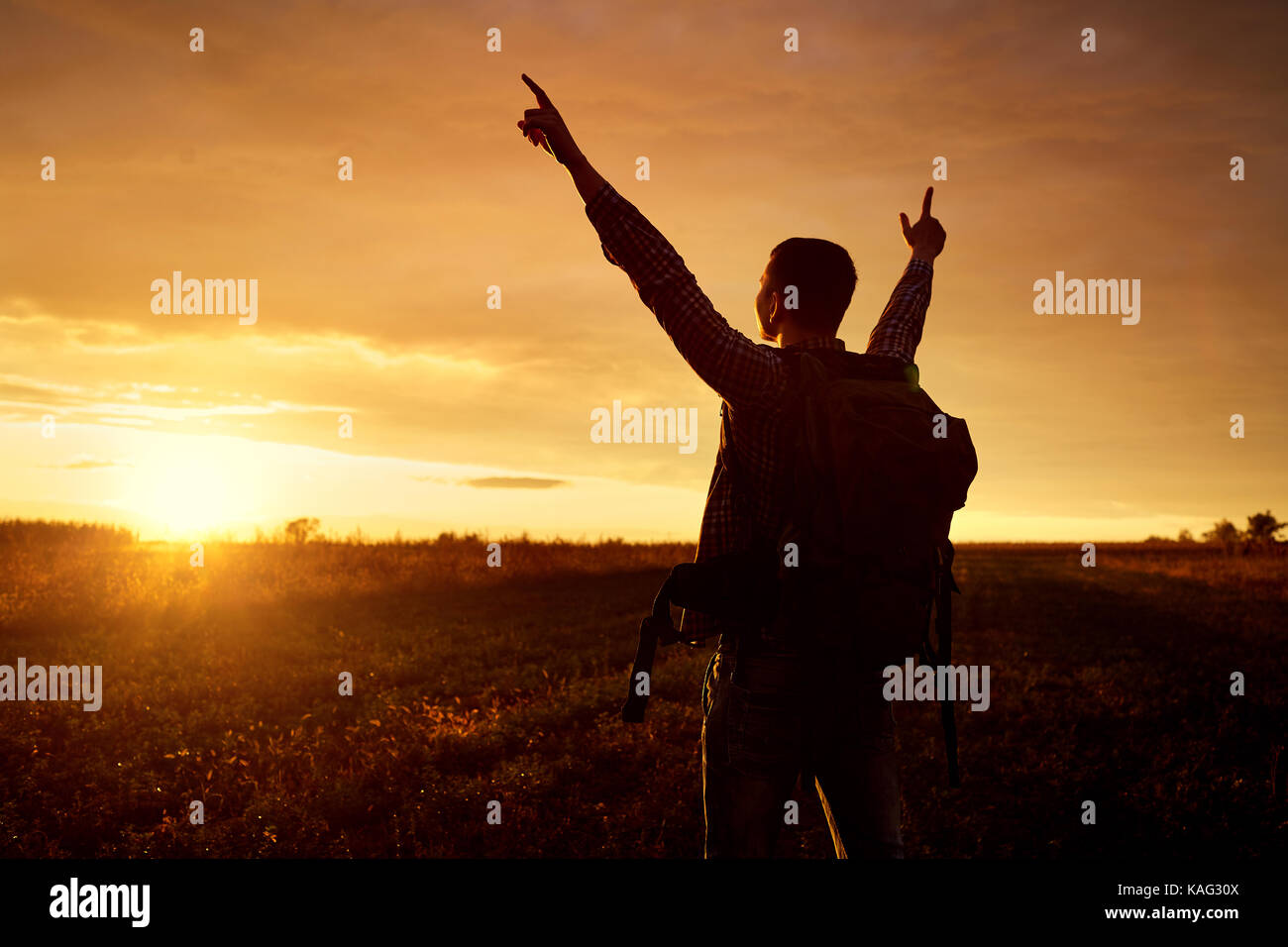 A traveler with a backpack lifted his hands up.  Stock Photo