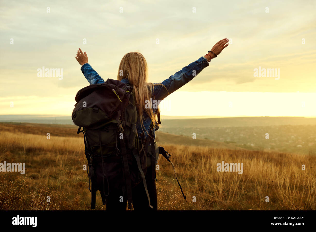 A traveler girl with a backpack lifted his hands up. Stock Photo