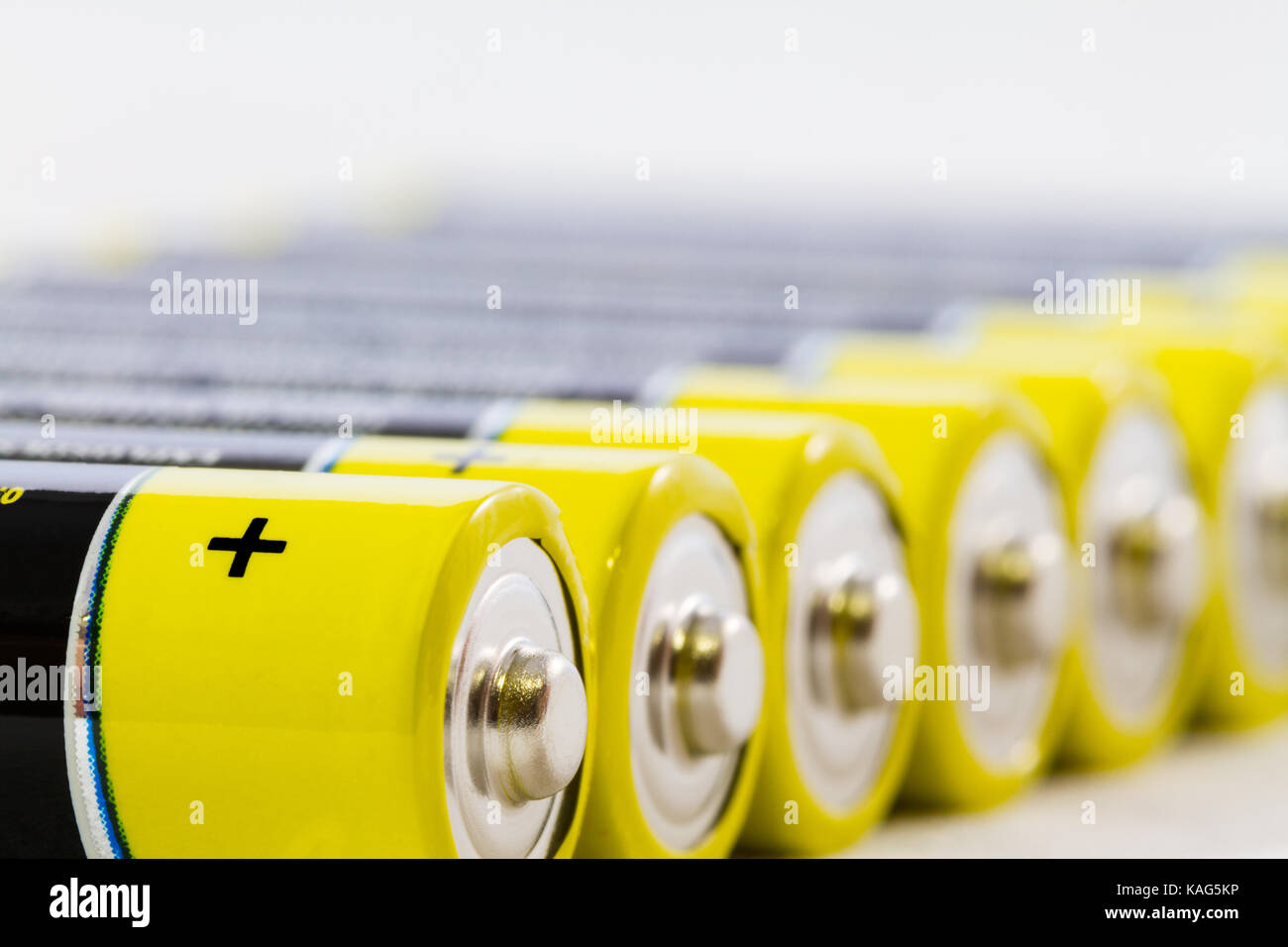 Diagonal row of yellow black AAA alkaline batteries isolated on a white