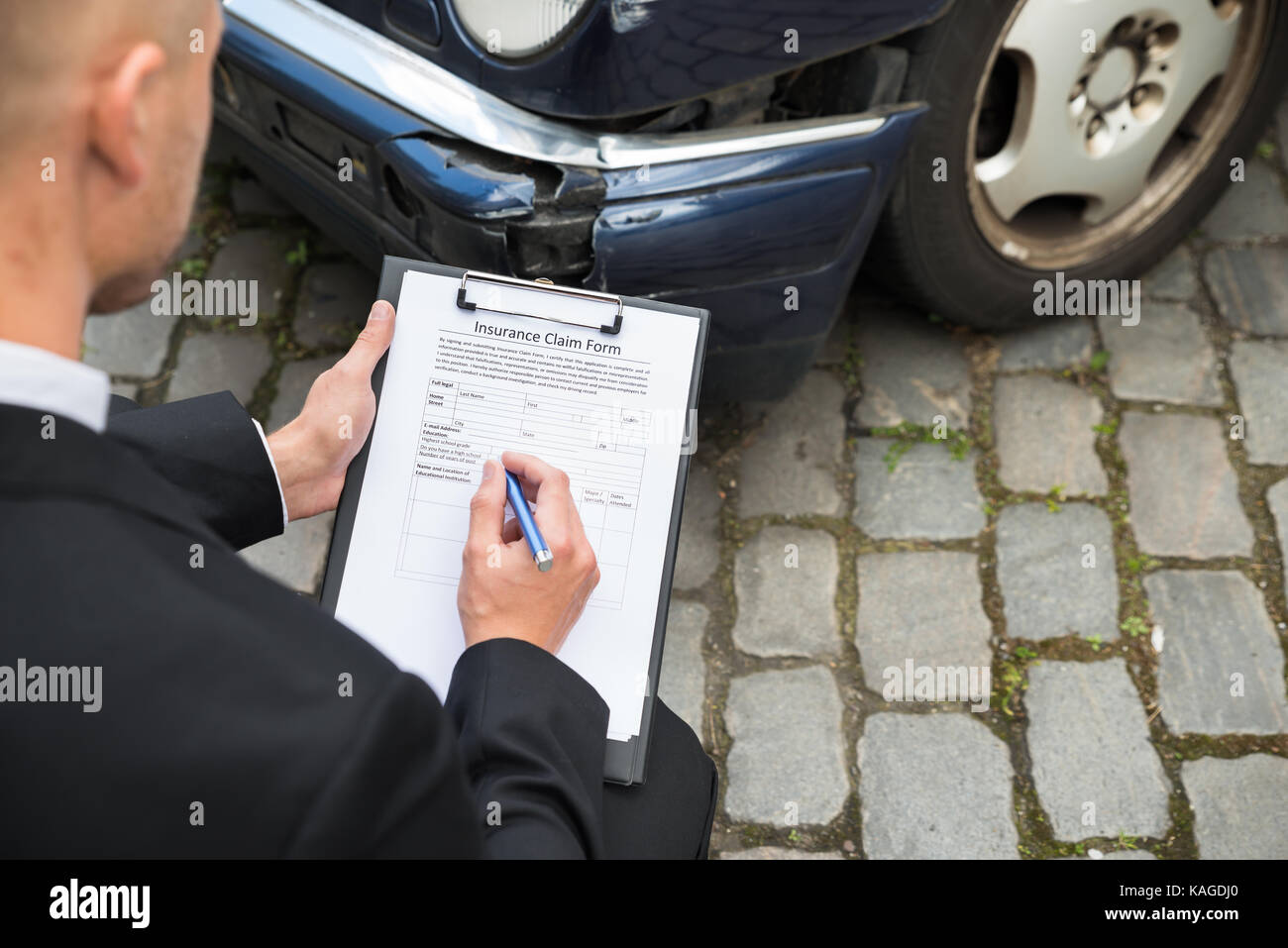 Close-up Of A Man Filling Insurance Form Near Damaged Car Stock Photo