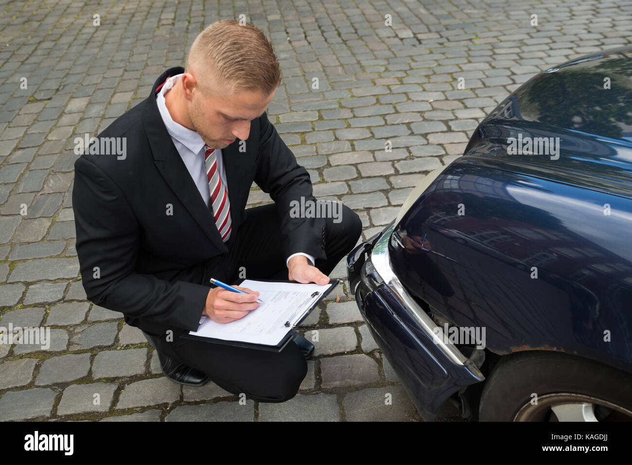 Close-up Of A Man Filling Insurance Form Near Damaged Car Stock Photo