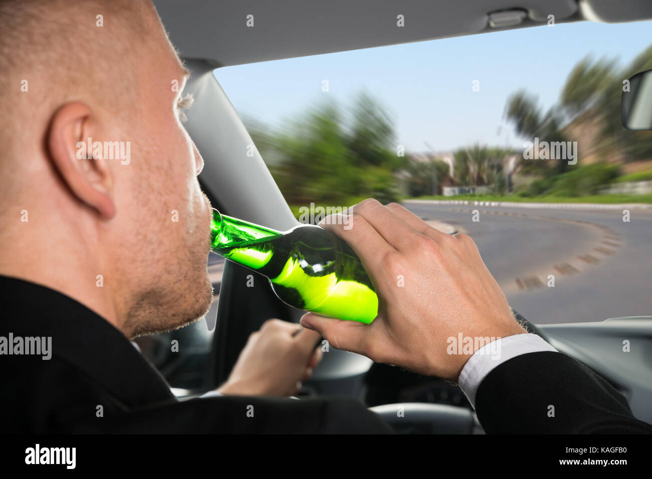 Close-up Of A Businessman Drinking Beer While Driving Car Stock Photo