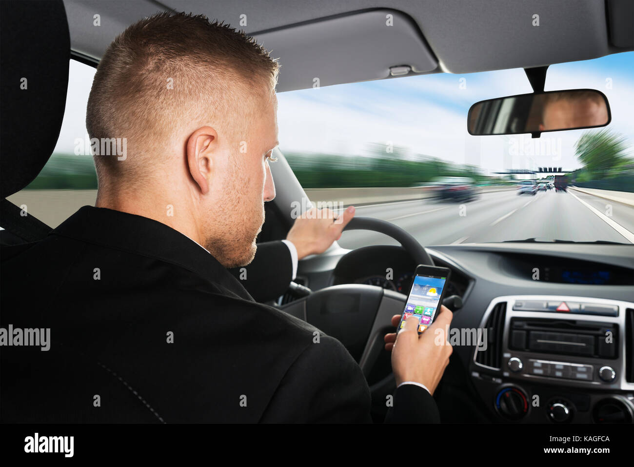Rear View Of A Businessman Using Cellphone While Driving Car Stock Photo