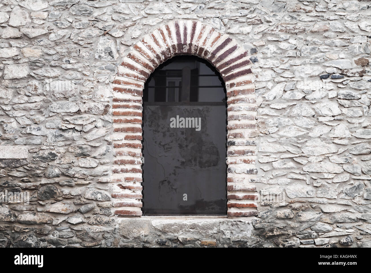 Arched window in old gray stone wall. Background photo texture Stock Photo