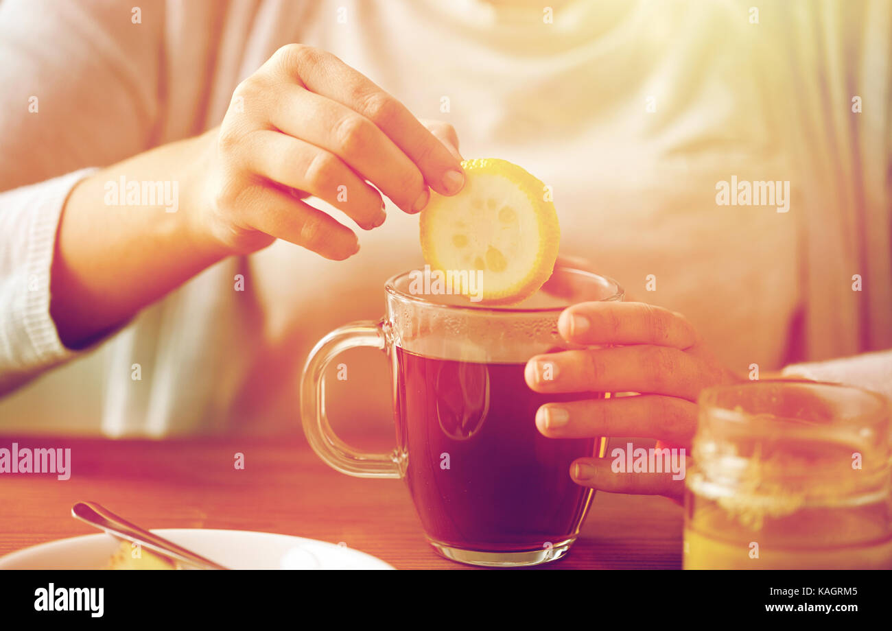 Close up of woman adding lemon to tea with honey stock photo alamy