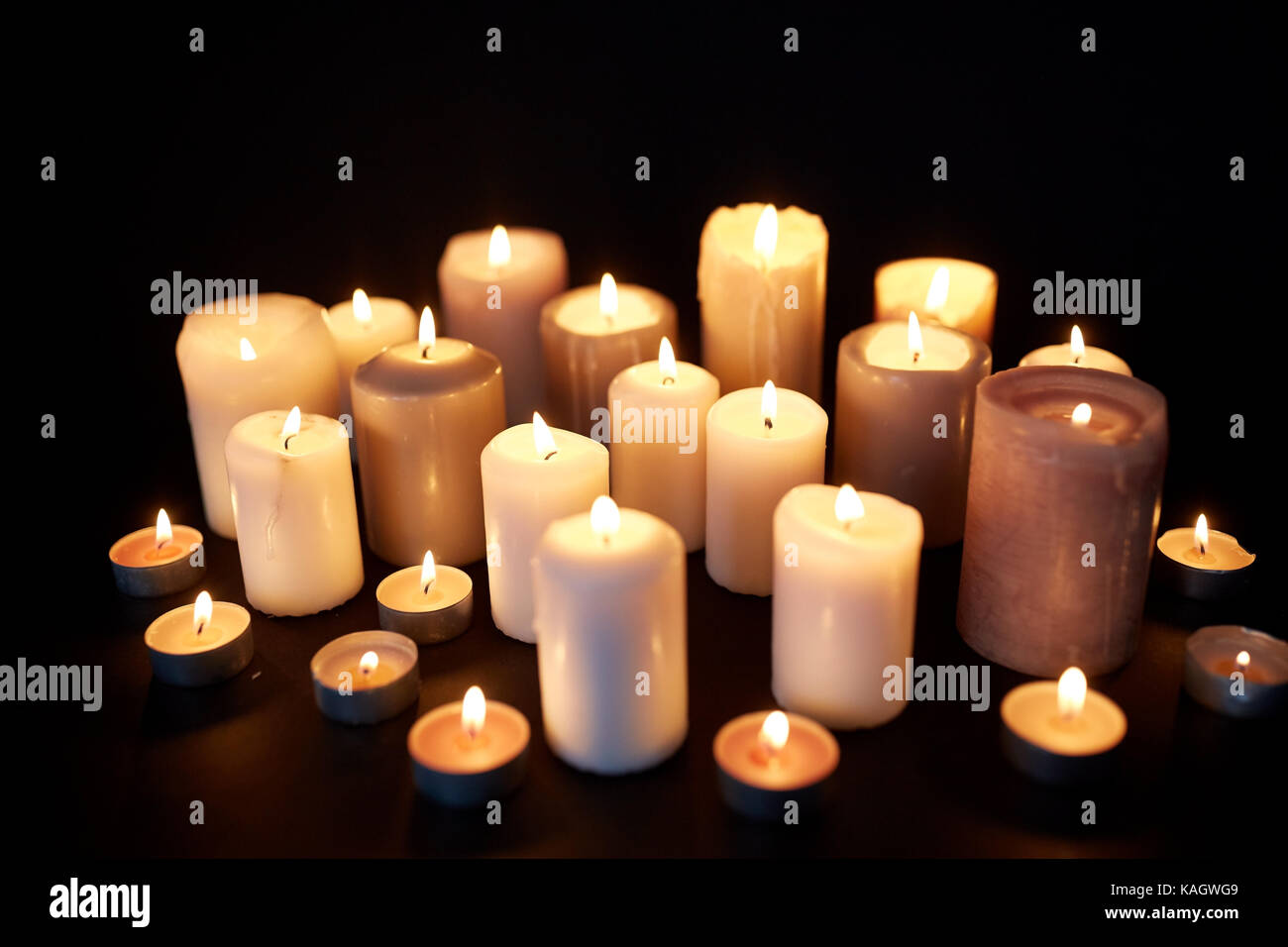 candles burning in darkness over black background Stock Photo - Alamy