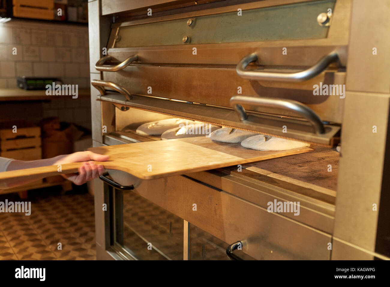 baker hand putting dough into bread oven at bakery Stock Photo Alamy