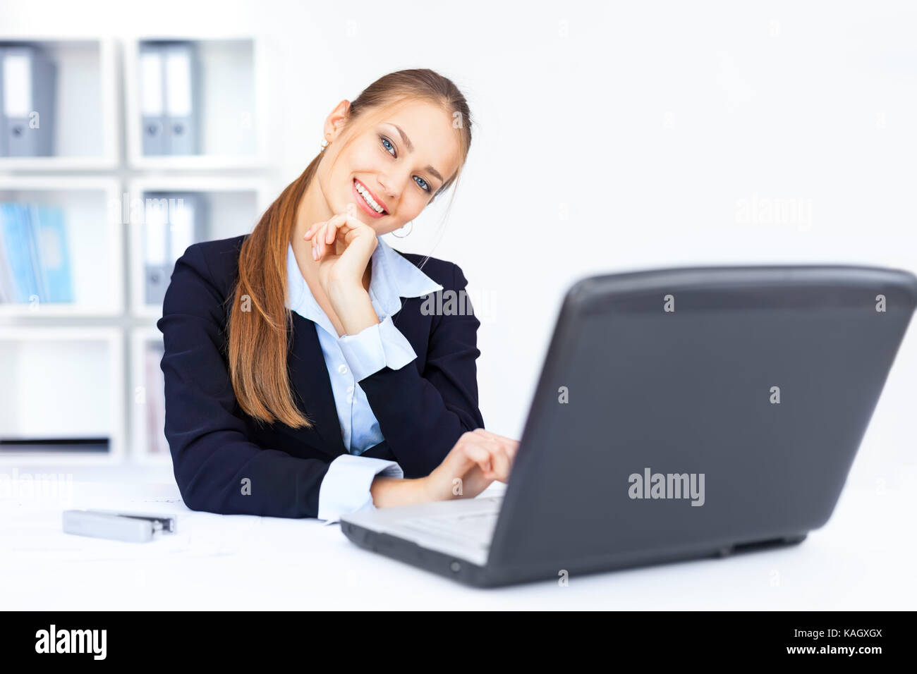 Portrait of beautiful young smiling business woman working on a laptop ...