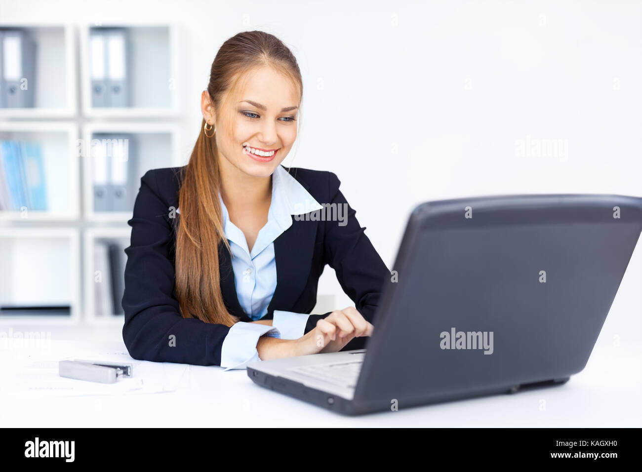 Portrait of beautiful young smiling business woman working on a laptop ...
