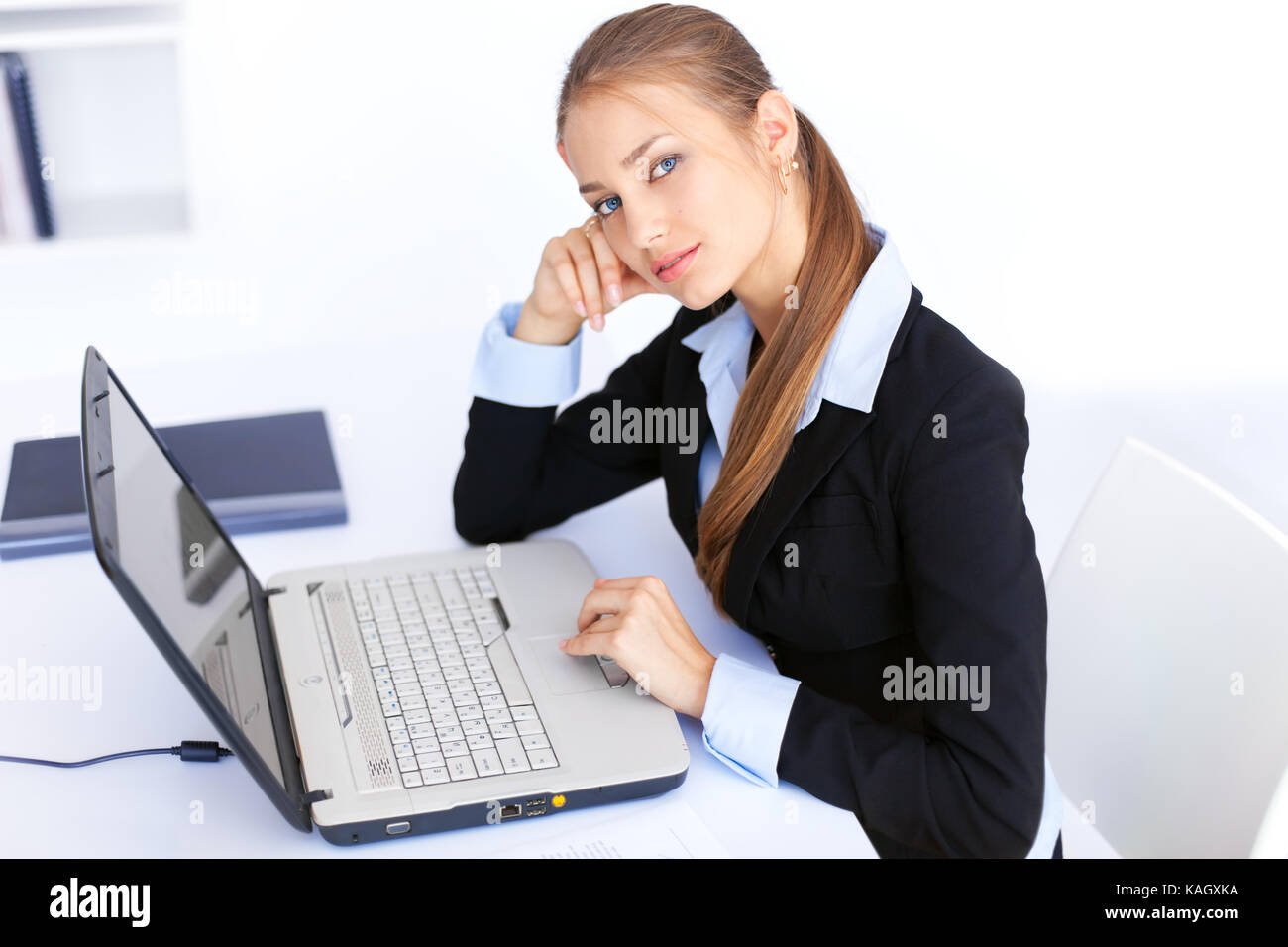 Portrait of beautiful young smiling business woman working on a laptop ...