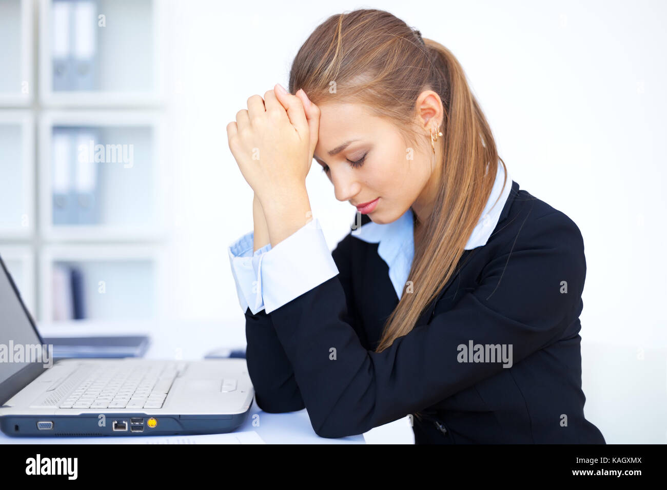 Portrait of tired young business woman with laptop computer at the ...