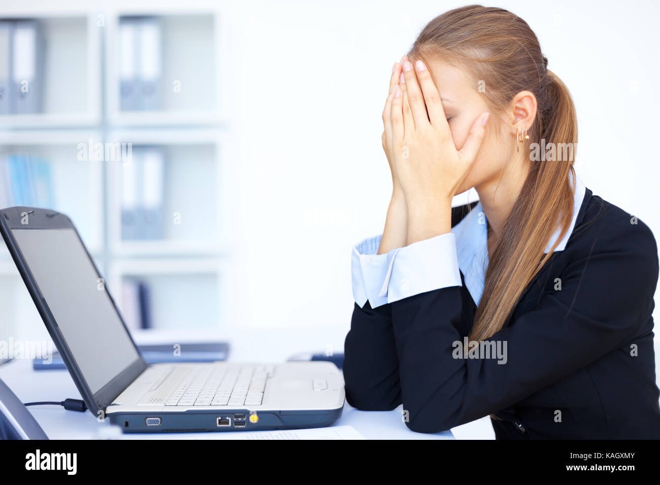 Portrait of tired young business woman with laptop computer at the ...