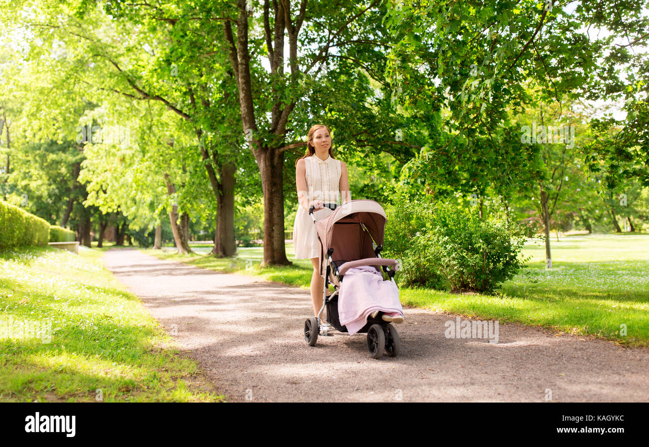 happy mother with child in stroller at summer park Stock Photo