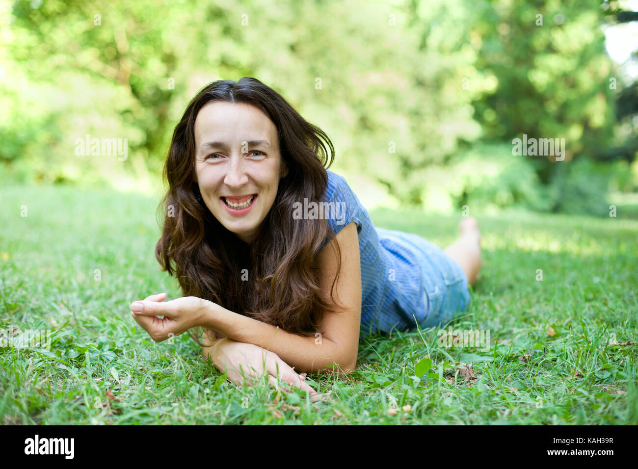 Beautiful young woman is lying on the green grass Stock Photo - Alamy