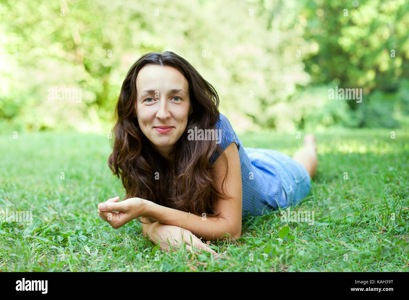 Beautiful young woman is lying on the green grass Stock Photo - Alamy