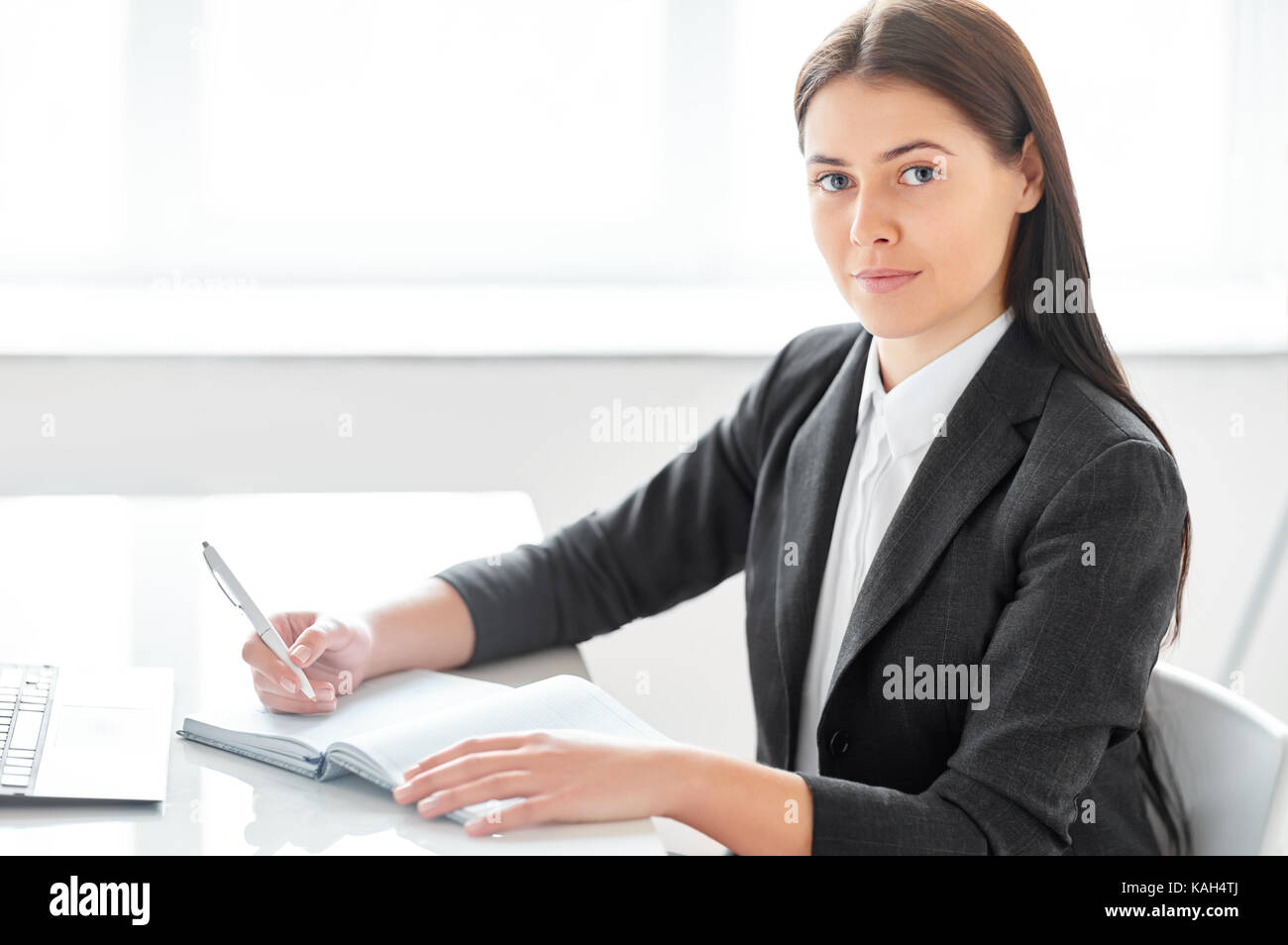 Portrait of young beautiful business woman with documents in the office ...