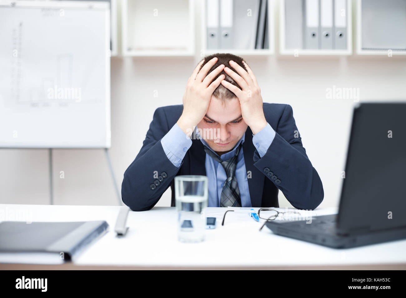 Depressed young business man holding his head at office Stock Photo - Alamy