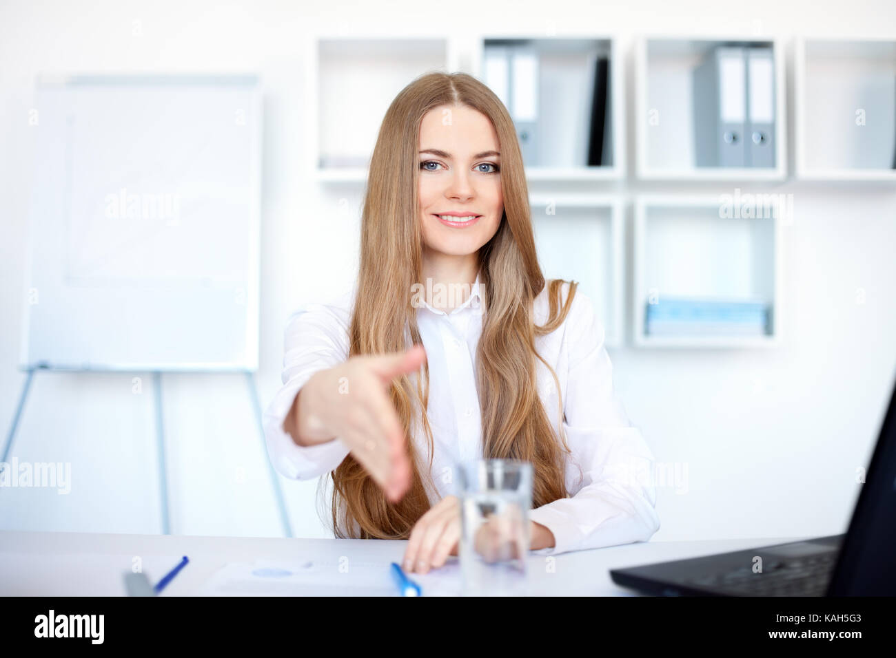 Portrait of beautiful young smiling business woman sitting at desk ...