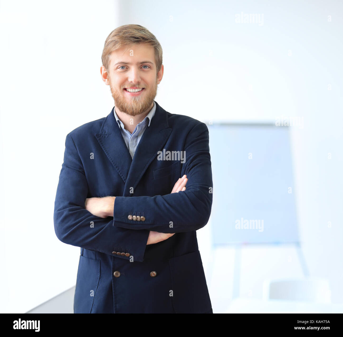 Portrait of young successful businessman in the office. Crossed arms ...