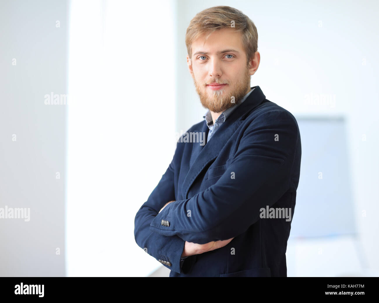 Portrait of young successful businessman in the office. Crossed arms ...
