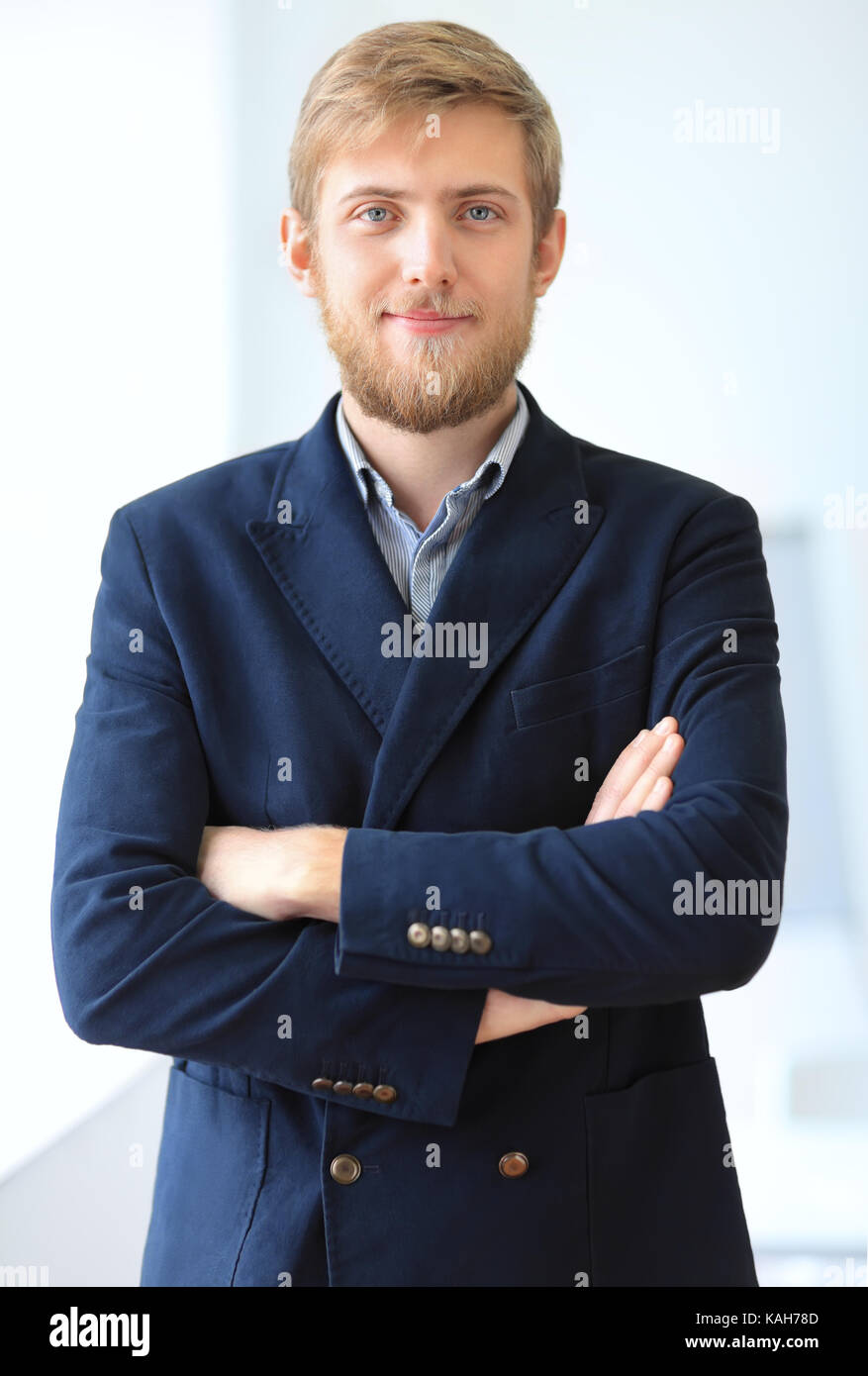 Portrait of young successful businessman in the office. Crossed arms ...