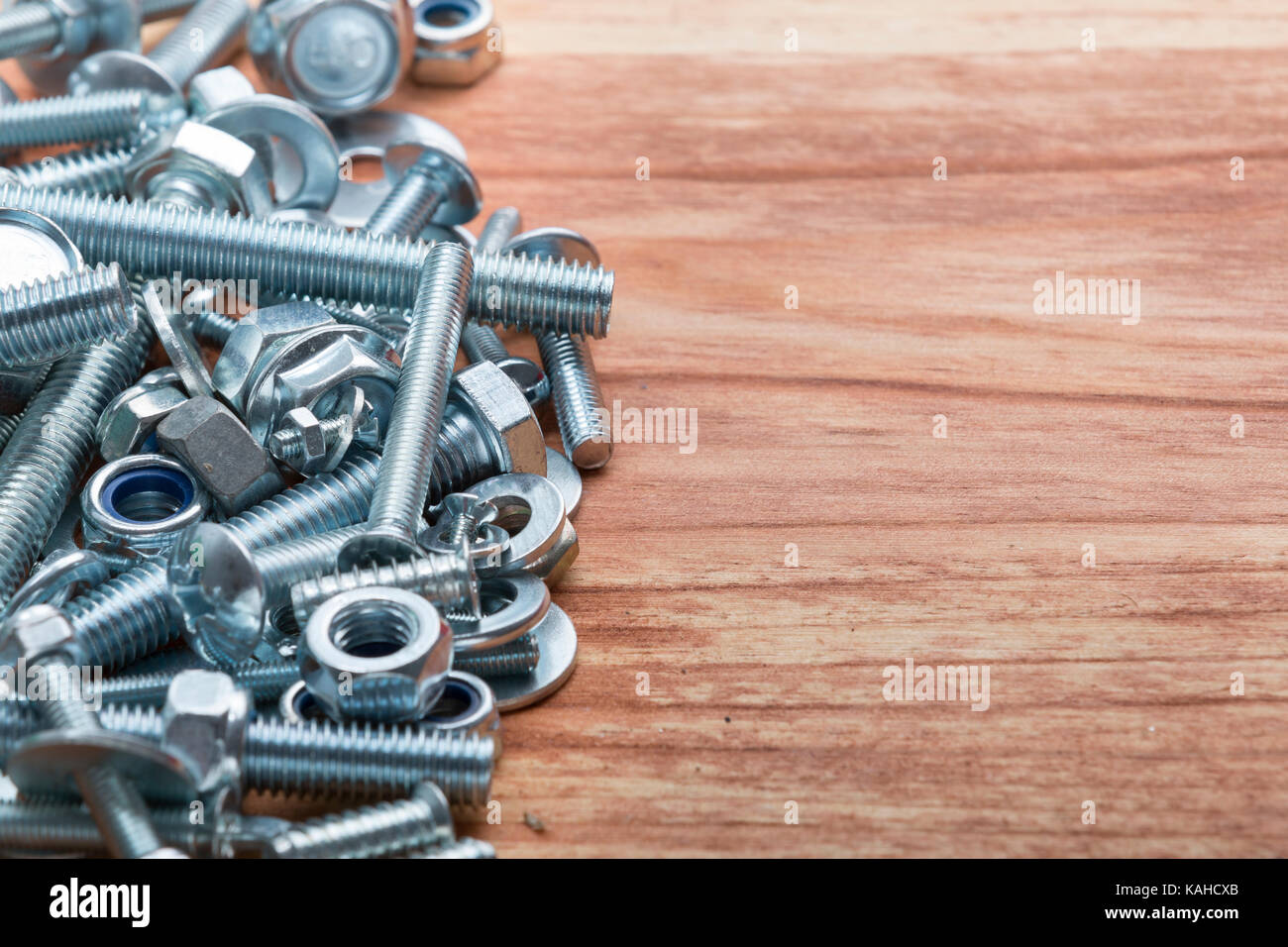 Pile of differents screws and bolts on wooden table. Background Stock