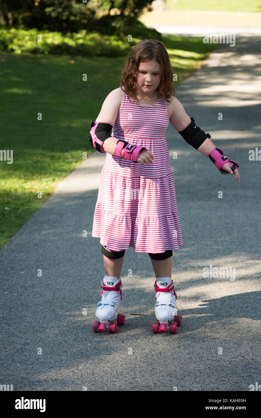 Little girl learning to roller skate in sunny summer park. Child wearing  protection elbow and knee pads, wrist guards and safety helmet for safe  rolle Stock Photo - Alamy