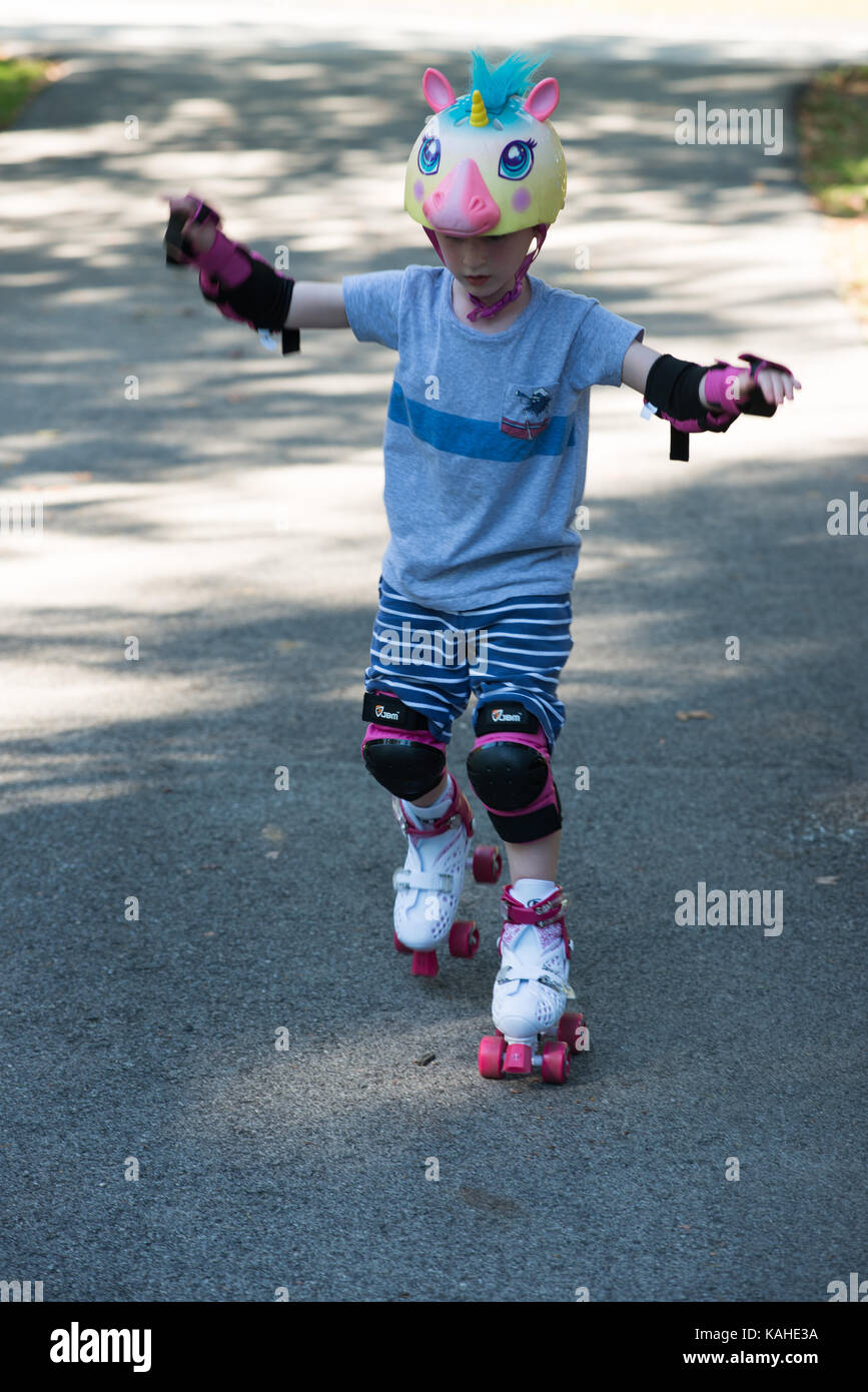 Little girl learning to roller skate in sunny summer park. Child wearing  protection elbow and knee pads, wrist guards and safety helmet for safe  rolle Stock Photo - Alamy