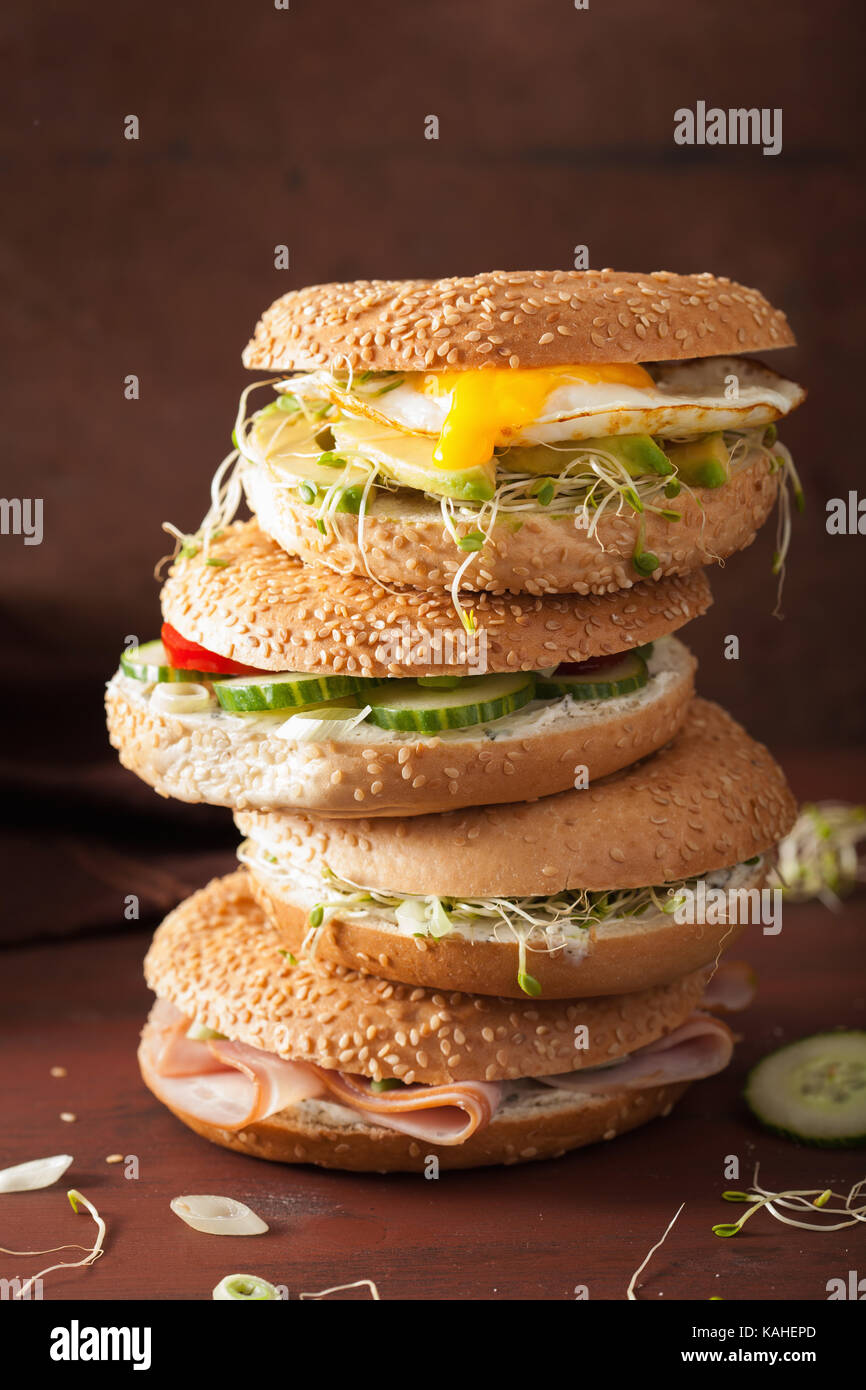 variety of sandwiches on bagels: egg, avocado, ham, tomato, soft cheese, alfalfa sprouts Stock Photo