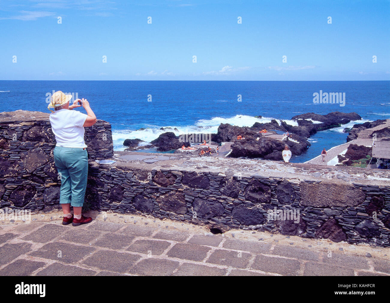 Elderly woman taking photos from the viewpoint. Garachico, Tenerife, Canary Islands, Spain. Stock Photo