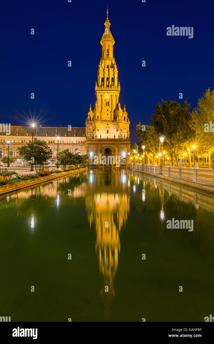 Tower reflected in water basin, illuminated Plaza de España, night view, Seville, Andalusia, Spain Stock Photo