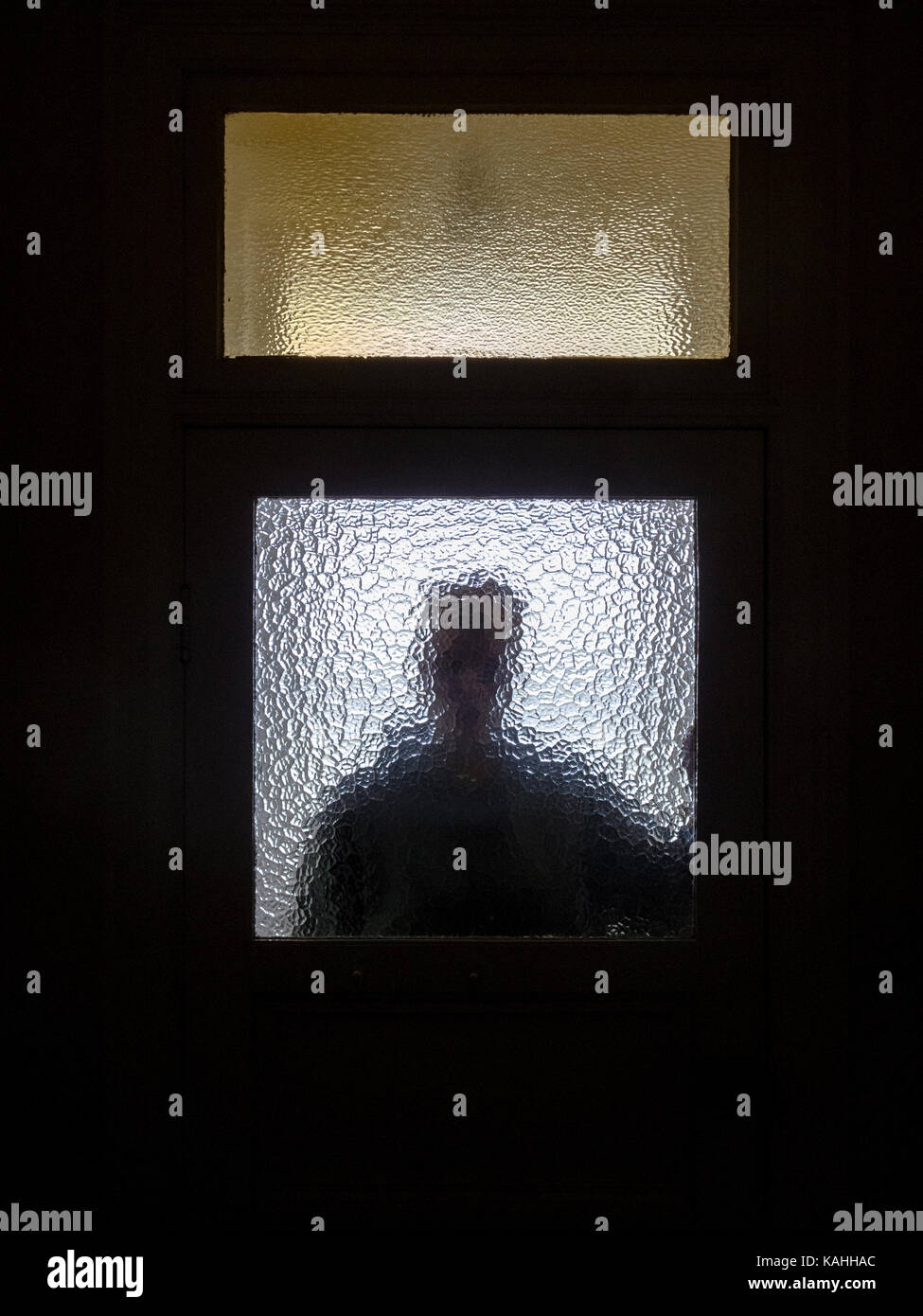 Silhouette of a person behind a stained glass door Stock Photo