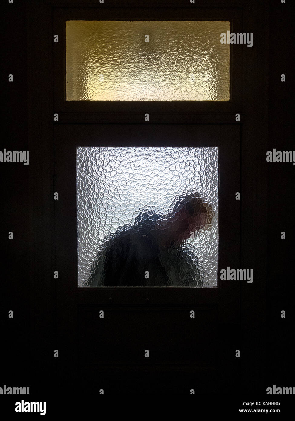 Silhouette of a person behind a stained glass door Stock Photo