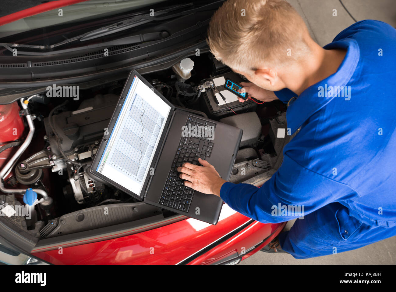 High Angle View Of Mechanic Using Laptop To Repair Car In Garage