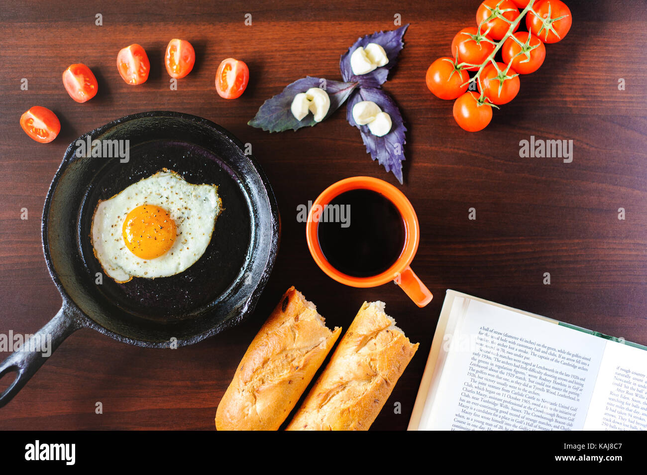 fried eggs mozzarella with basil and tomatoes on a frying pan Stock