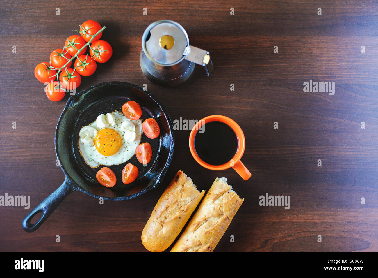 fried eggs mozzarella with basil and tomatoes on a frying pan Stock